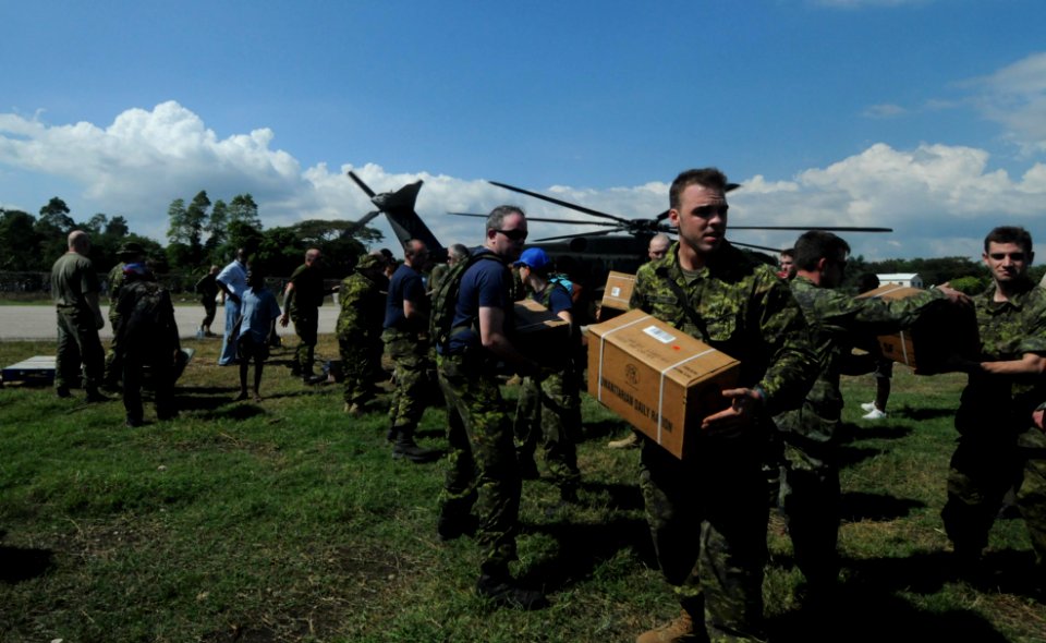 US Navy 100120-N-4995K-198 Canadian soldiers and Haitian citizens unload food and water from an MH-53E Sea Dragon helicopter
