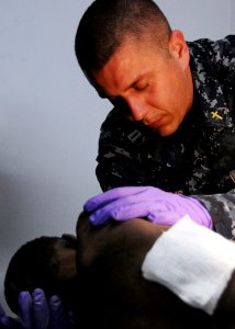 US Navy 100120-N-6247V-034 Lt. Marlin Williams prays for a Haitian boy as he receives treatment at the Killick Haitian Coast Guard Clinic photo