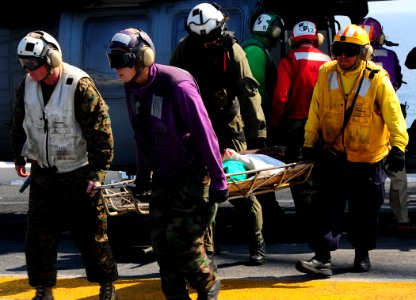 US Navy 100120-N-7508R-213 Fight deck crew members aboard USS Bataan (LHD 5) carry a Haitian woman to the ship's flight deck triage for immediate medical treatment