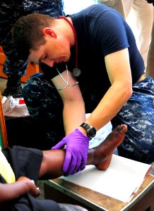 US Navy 100123-N-4774B-228 Chief Hospital Corpsman Shawn Kirkpatrick, assigned to the guided-missile cruiser USS Normandy (CG 60), treats a Haitian woman