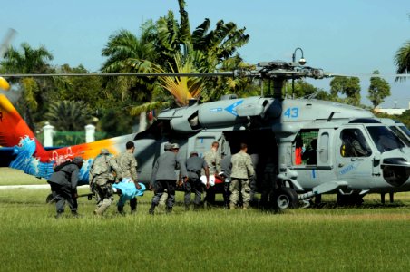 US Navy 100121-N-6410J-116 U.S. Army soldiers and Haitian service members rush medical patients to an MH-60S Sea Hawk helicopter