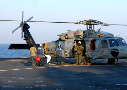US Navy 100124-N-4971L-046 Sailors aboard USS Fort McHenry (LSD 43) carry injured Haitian medical evacuees to an MH-60S Sea Hawk helicopter