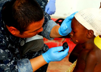 US Navy 100122-N-5244H-099 Hospital Corpsman 3rd Class Sergio Hernandez examines a young Haitian patient at the Hope Estate Medical Clinic in Neply, Haiti