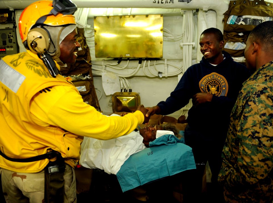 US Navy 100122-N-5345W-028 A Haitian man shakes the hand of Chief Warrant Officer Wilfrid Bossous before being transported with his mother to USNS Comfort (T-AH 20)