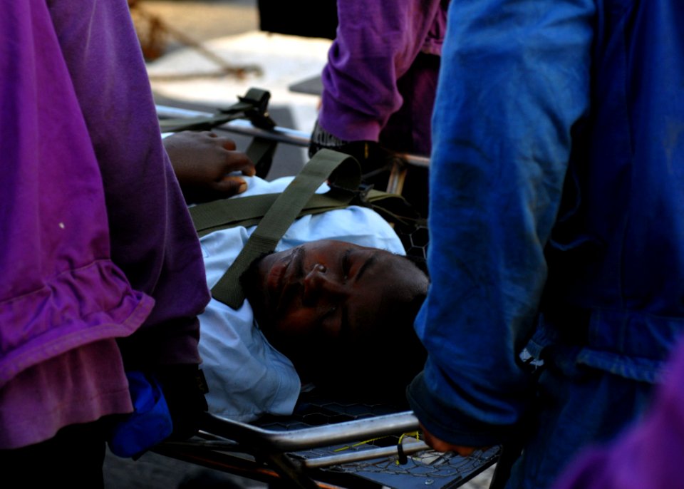 US Navy 100124-N-4971L-086 Sailors aboard USS Fort McHenry (LSD 43) carry injured Haitian medical evacuees to an MH-60S Sea Hawk helicopter