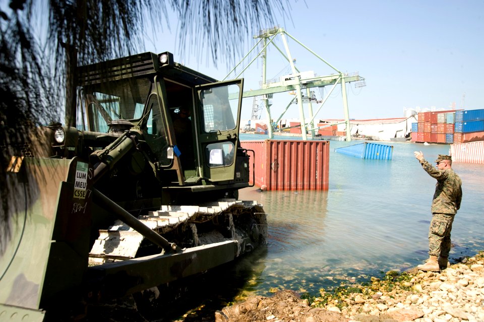 US Navy 100125-N-1134L-089 Service members working with U.S. Marine Corps 8th Engineer Support Battalion use a bulldozer to remove submerged container boxes