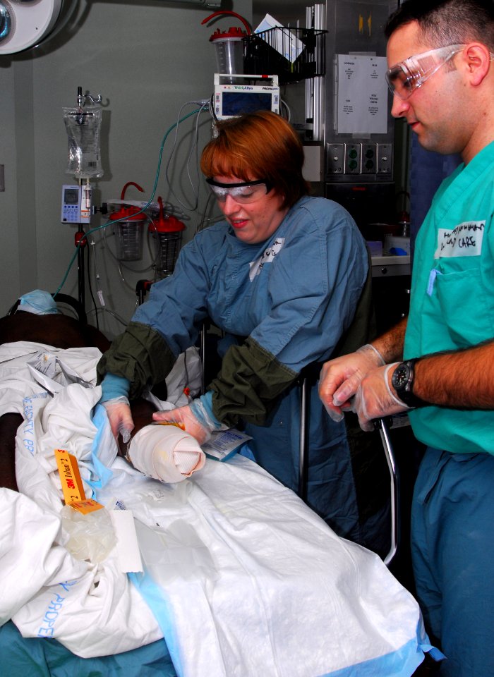 US Navy 100125-N-4047W-019 Lt. Cmdr. Felecia Smith and Hospital Corpsman 2nd Class Steven Buckingham dress the bandage on an amputee patient aboard the Military Sealift Command hospital ship USNS Comfort (T-AH 20)