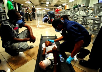 US Navy 100123-N-2953W-450 A Sailor aboard the Nimitz-class aircraft carrier USS Carl Vinson (CVN 70), comforts a young Haitian boy after the ship's medical staff performed live-saving surgery