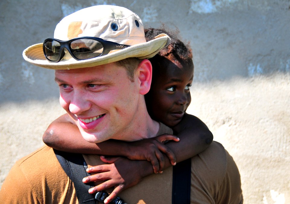 US Navy 100123-N-4774B-572 A Sailor assigned to the guided-missile cruiser USS Normandy (CG 60) carries a Haitian child during a site assessment
