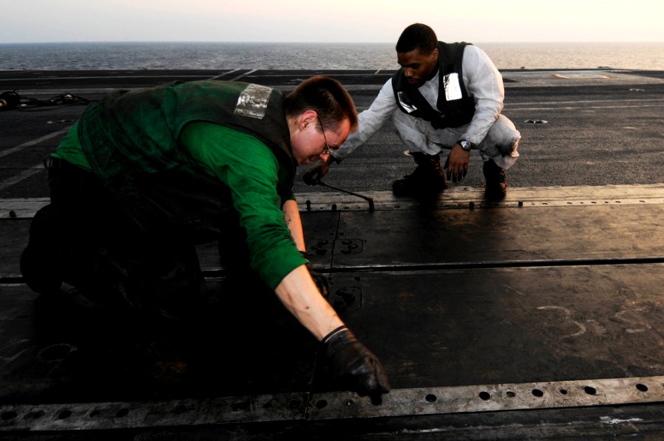 US Navy 100123-N-3038W-036 Aviation Boatswain's Mate (Equipment) Airmen Paul Maxon and Christopher Hope perform maintenance on a catapult aboard the aircraft carrier USS Nimitz (CVN 68)