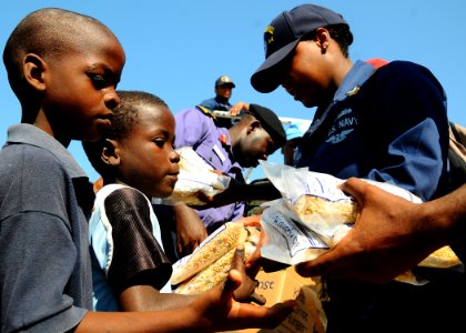 US Navy 100122-N-8655E-567 Logistics Specialist 1st Class Michauli Martin and Nigerian navy Capt. Adejimi Osinowo pass out bags of rice to Haitian civilians