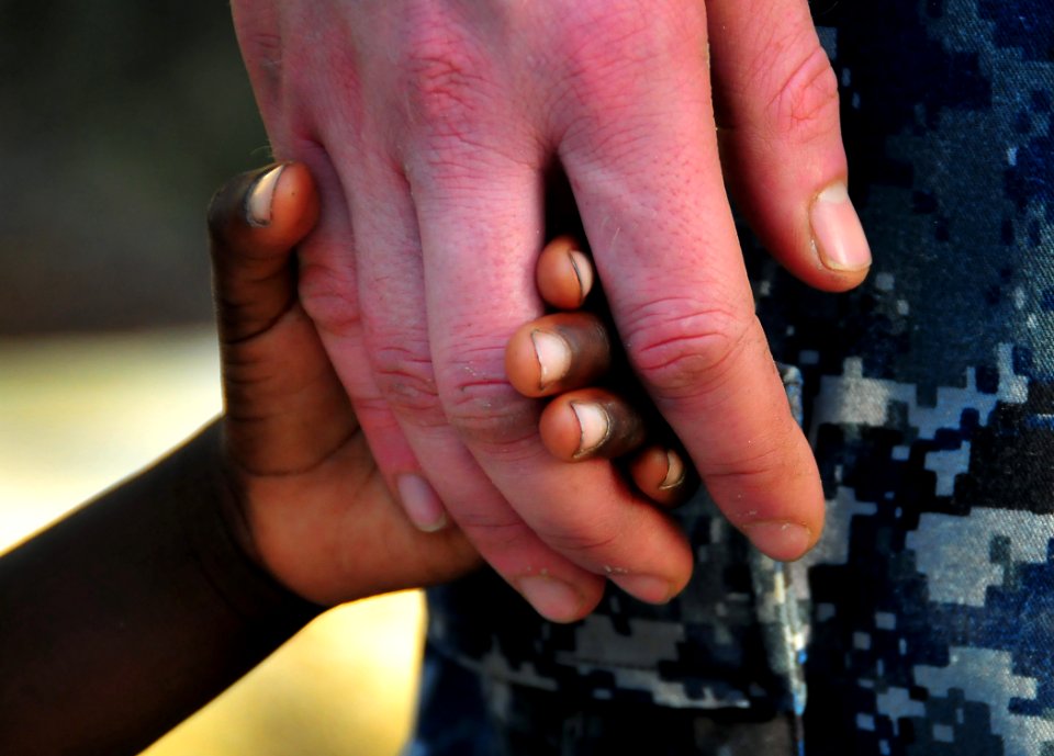 US Navy 100123-N-4774B-840 Ensign Adam Cole holds hands with a Haitian girl during an assessment visit