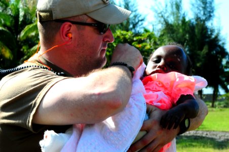 US Navy 100123-N-7508R-028 Chief Warrant Officer Jason Taggart prepares to medivac a Haitian child to a nearby treatment facility photo