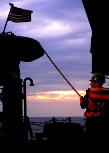 US Navy 100125-N-5244H-004 Seaman Jesse Willson steadies a rigid-hull inflatable boat as it is craned onto the deck of amphibious dock landing ship USS Carter Hall (LSD 50)