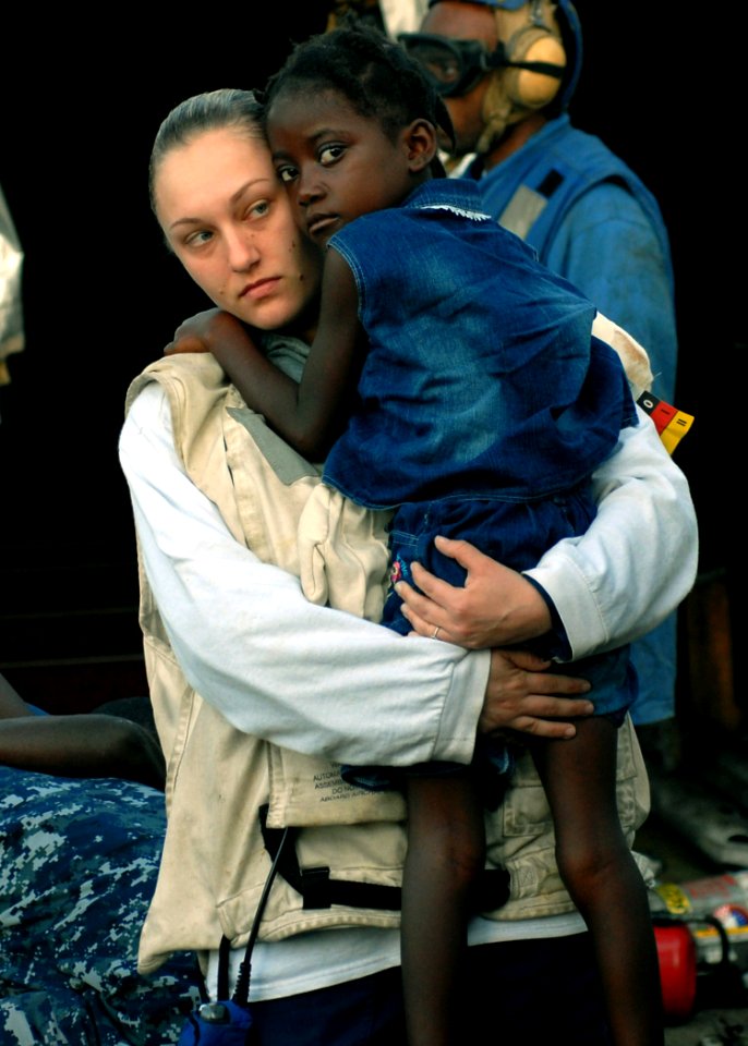 US Navy 100124-N-4971L-039 Hospital Corpsman 3rd Class Katie Blankenship carries an injured Haitian girl aboard USS Fort McHenry (LSD 43) to an MH-60S Sea Hawk helicopter