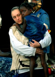 US Navy 100124-N-4971L-039 Hospital Corpsman 3rd Class Katie Blankenship carries an injured Haitian girl aboard USS Fort McHenry (LSD 43) to an MH-60S Sea Hawk helicopter