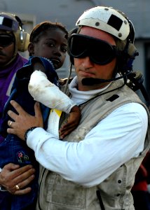 US Navy 100124-N-4971L-058 Lt.j.g. Jeffrey Dolan carries an injured Haitian girl to an MH-60S Sea Hawk helicopter photo