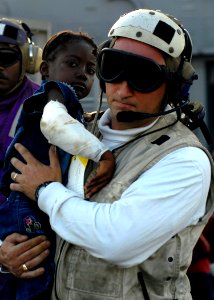 US Navy 100124-N-4971L-058 Lt.j.g. Jeffrey Dolan carries an injured Haitian girl to an MH-60S Sea Hawk helicopter