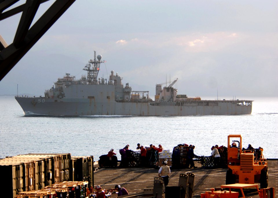 US Navy 100125-N-4971L-389 Sailors and Marines onload stores and relief supplies aboard the amphibious dock landing ship USS Fort McHenry (LSD 43) as the amphibious dock landing ship USS Carter Hall (LSD 50) passes by
