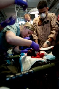 US Navy 100125-N-5712P-025 Sailors close a laceration on the right wrist of a medical evacuee from Haiti being treated aboard the amphibious assault ship USS Nassau (LHA 4) photo