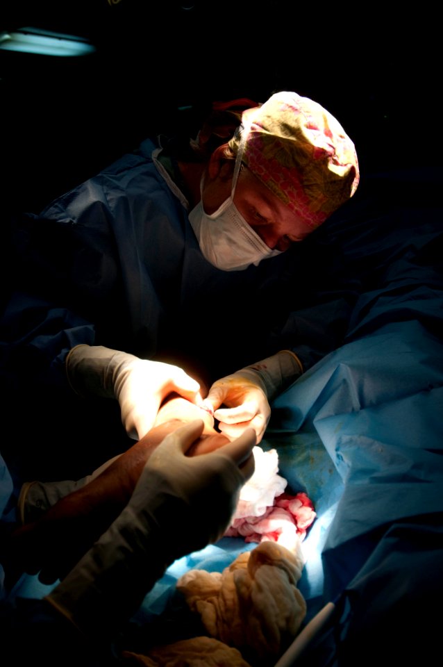 US Navy 100125-N-5712P-172 Medical personnel perform a surgical procedure on a a medical evacuee from Haiti being treated aboard the amphibious assault ship USS Nassau (LHA 4)