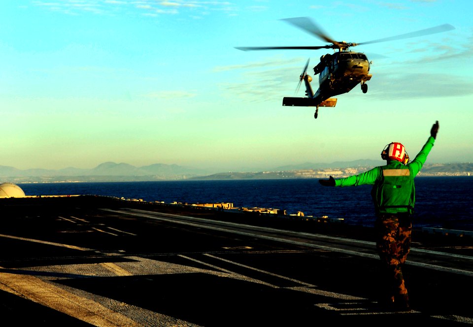 US Navy 100124-N-9928E-011 Aviation Electrician's Mate 3rd Class Bryan Darlington, from Akron, Ohio, signals an MH-60S Sea Hawk helicopter