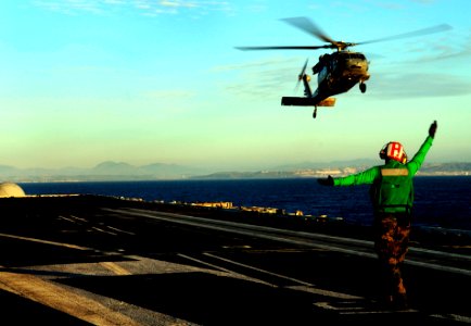 US Navy 100124-N-9928E-011 Aviation Electrician's Mate 3rd Class Bryan Darlington, from Akron, Ohio, signals an MH-60S Sea Hawk helicopter photo