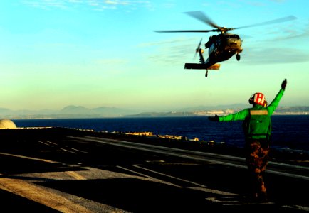 US Navy 100124-N-9928E-011 Aviation Electrician's Mate 3rd Class Bryan Darlington, from Akron, Ohio, signals an MH-60S Sea Hawk helicopter