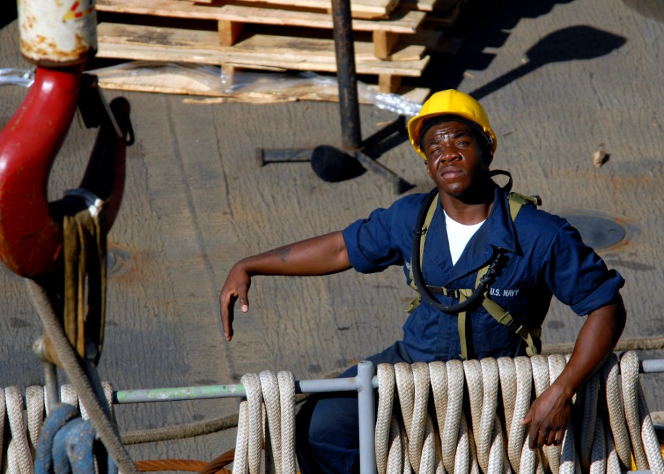 US Navy 100125-N-4971L-014 Seaman Antonio Shipman signals a crane operator as heavy equipment is moved aboard the amphibious dock landing ship USS Fort McHenry (LSD 43) to make room for relief supplies