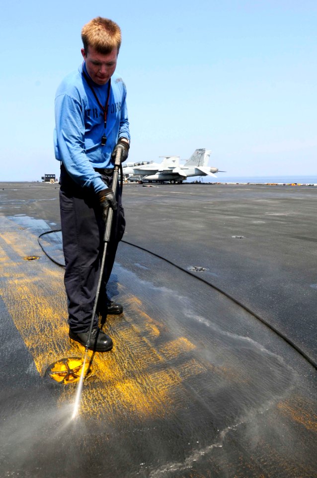 US Navy 100126-N-3038W-122 Aviation Boatswains Mate (Handling) Airman Joseph Leroy washes the flight deck center line aboard the aircraft carrier USS Nimitz (CVN 68)