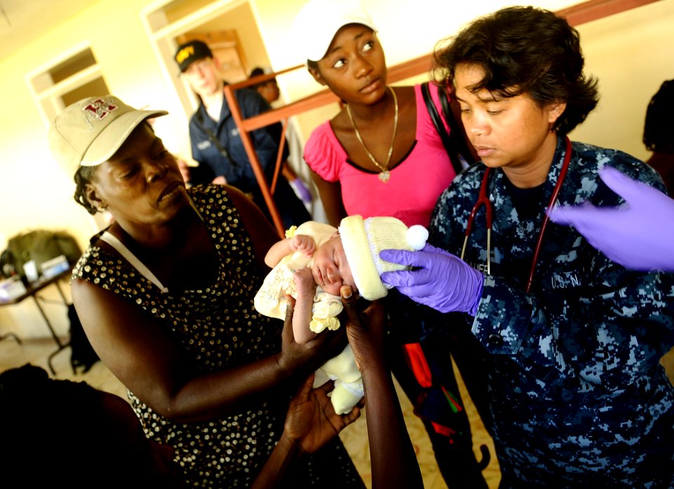 US Navy 100125-N-5345W-094 Hospital Corpsman 1st Class Vilma Bauer, assigned to the amphibious dock landing ship USS Fort McHenry (LSD 43) examines a Haitian infant as her family looks on