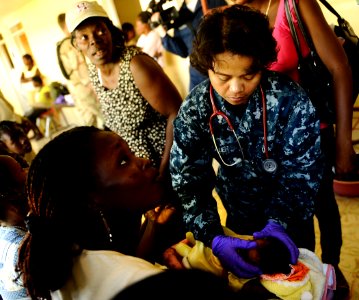 US Navy 100125-N-5345W-098 Hospital Corpsman 1st Class Vilma Bauer examines a Haitian infant at the Lifeline Christian Ministries Mission medical clinic in Grand Goave photo