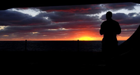 US Navy 100127-N-2858S-377 Personnel Specialist Seaman Payton Yancy watches a sunset from the hangar bay aboard the Nimitz-class aircraft carrier USS Harry S. Truman (CVN 75)