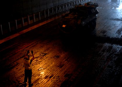 US Navy 100125-N-8607R-046 Lance Cpl. Daniel Aguilera directs a light armored vehicle (LAV-25) in the well deck of the amphibious assault ship USS Bonhomme Richard (LHD 6)