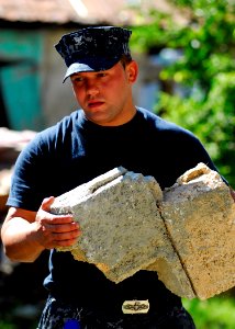 US Navy 100127-N-5244H-052 Electronics Technician 3rd Class Dwight Clark removes broken cinder blocks from the rubble of a home in Neply, Hait photo