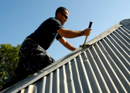 US Navy 100127-N-7638K-120 Ensign Maccon Buchanan, from Raleigh, N.C. assigned to the amphibious dock landing ship USS Fort McHenry (LSD 43), repairs a damaged roof on LuGonave Island, Haiti