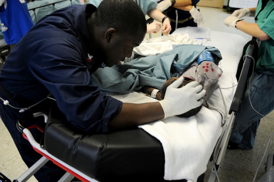 US Navy 100126-N-4995K-093 Quartermaster 2nd Class Edder Bazne, a translator aboard the Military Sealift Command hospital ship USNS Comfort (T-AH 20), consoles a 12-year-old girl in the Comfort post operation ward