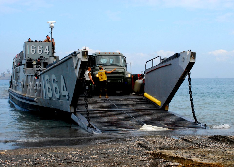 US Navy 100126-N-5244H-001 Seabees off-load heavy equipment from a landing craft unit on the shore of Bonel