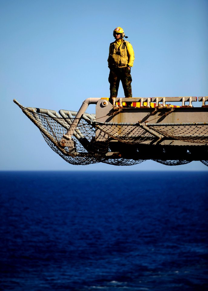 US Navy 100127-N-5345W-024 An aircraft director watches from a flight deck elevator as the multi-purpose amphibious assault ship USS Bataan (LHD 5)