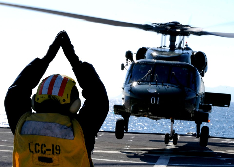 US Navy 100126-N-7478G-166 Boatswain's Mate 3rd Class Christine Bagley signals an approaching SH-60F Sea Hawk helicopter aboard the U.S. 7th Fleet command ship USS Blue Ridge (LCC 19)