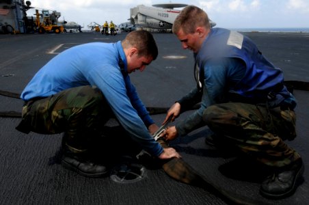 US Navy 100127-N-3038W-043 Aviation Boatswain's Mate (Handling) Airman Jon Bonvissuto and Aviation Boatswain's Mate Airman (Handling) Joshua Bourdon connect a fire hose on the flight deck aboard the aircraft carrier USS Nimitz photo