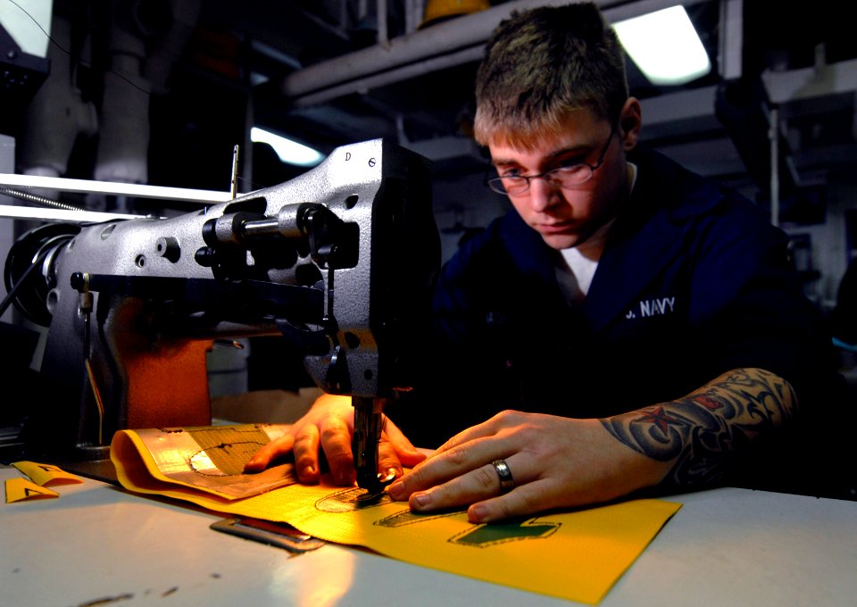 US Navy 100127-N-2475A-075 Seaman Nick Mason sews numbers onto a distance flag for a phone and distance line in the bunting shop aboard the Nimitz-class aircraft carrier USS John C. Stennis (CVN 74)