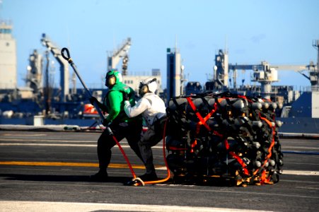 US Navy 100127-N-2953W-392 Flight deck crew members aboard the Nimitz-class aircraft carrier USS Carl Vinson (CVN 70) attach a hook to a MH-60S Sea Hawk helicopter during a vertical replenishment