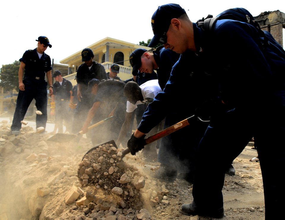 US Navy 100126-N-8655E-675 Haitian citizens and Sailors assigned to the multi-purpose amphibious assault ship USS Bataan (LHD 5) shovel rubble and debris from the roads in Grande Goave, Haiti