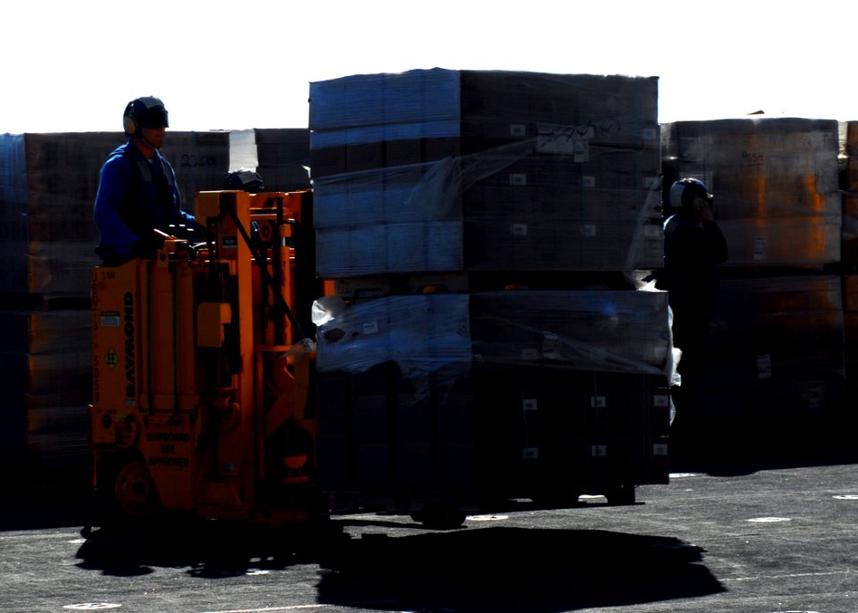 US Navy 100127-N-3165S-153 A Sailor transfers pallets of meals-ready-to-eat into the ship's hangar bay for distribution in the relief efforts in Haiti