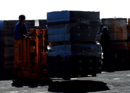 US Navy 100127-N-3165S-153 A Sailor transfers pallets of meals-ready-to-eat into the ship's hangar bay for distribution in the relief efforts in Haiti