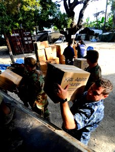 US Navy 100127-N-7948C-032 Hospital Corpsman 1st Class Matthew Evans loads humanitarian aid boxes onto a U.N. truck at Killick Haitian Coast Guard Base photo