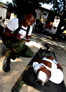 US Navy 100129-N-6676S-002 A Haitian aid worker screens a patient before he is treated at the Killick Haitian Coast Guard Base photo