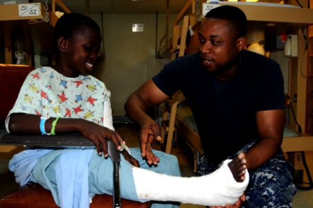 US Navy 100129-N-6410J-013 Culinary Specialist 3rd Class Jean-Jurolien speaks to a young Haitian patient in the pediatric ward aboard the Military Sealift Command hospital ship USNS Comfort (T-AH 20)