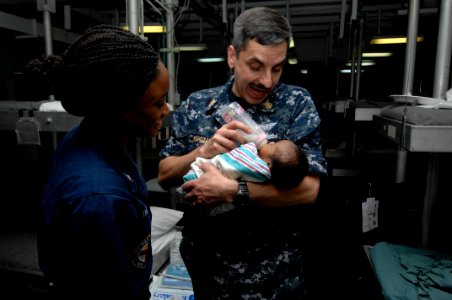 US Navy 100129-N-8936G-023 Master Chief Stanley Kopiczak, command master chief of the amphibious assault ship USS Nassau (LHA 4), feeds an infant girl in Nassau's medical department photo
